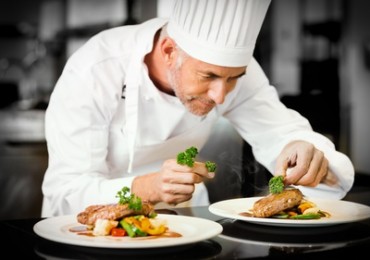 Concentrated male chef garnishing food in kitchen